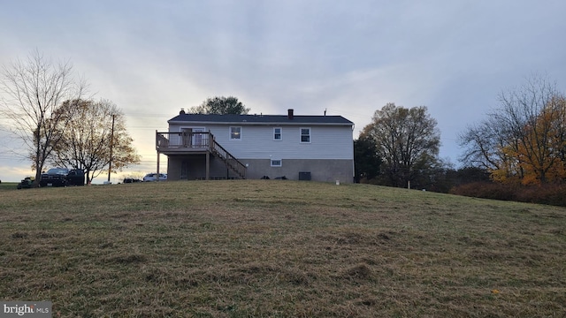 back house at dusk featuring a yard and a deck