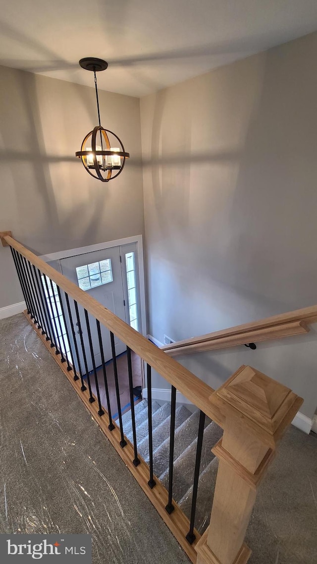 stairway featuring carpet and a notable chandelier