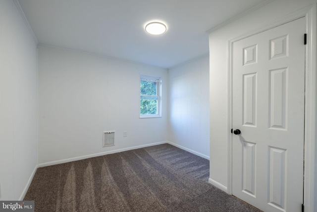 unfurnished room with crown molding and dark carpet