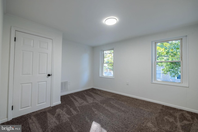 unfurnished room with dark carpet