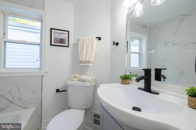 bathroom featuring vanity, toilet, plenty of natural light, and a bathing tub