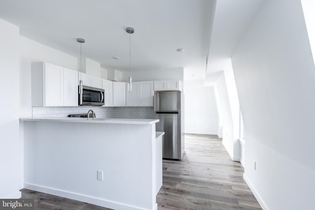 kitchen with kitchen peninsula, backsplash, stainless steel appliances, light hardwood / wood-style flooring, and white cabinets