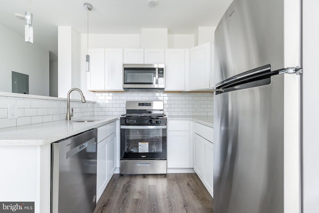 kitchen featuring white cabinets, sink, decorative light fixtures, wood-type flooring, and stainless steel appliances