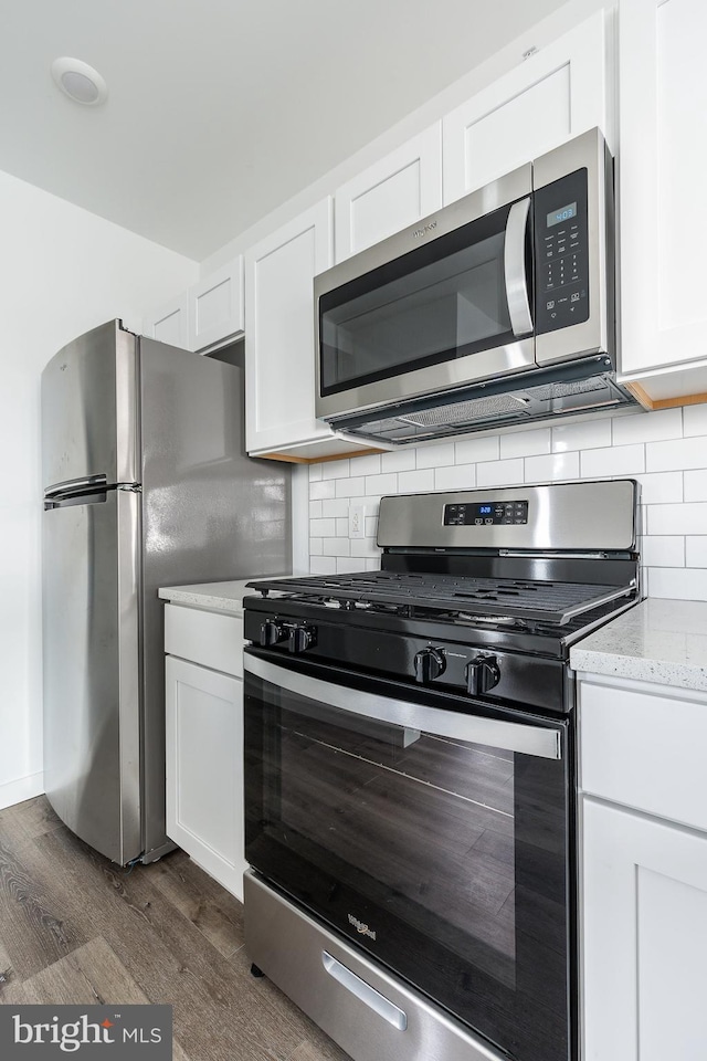 kitchen with appliances with stainless steel finishes, dark hardwood / wood-style flooring, and white cabinetry