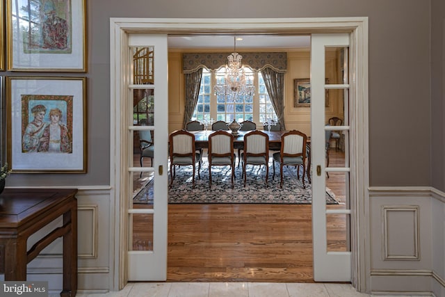 dining space with french doors, light tile patterned flooring, and an inviting chandelier