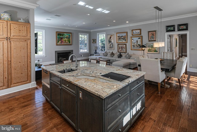 kitchen with dark hardwood / wood-style flooring, a kitchen island with sink, crown molding, sink, and hanging light fixtures