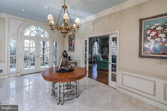 entrance foyer featuring light hardwood / wood-style floors, an inviting chandelier, crown molding, and french doors