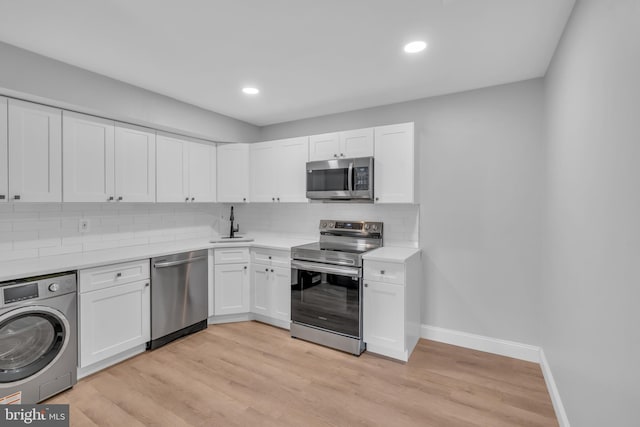 kitchen featuring light wood-type flooring, tasteful backsplash, stainless steel appliances, white cabinets, and washer / dryer