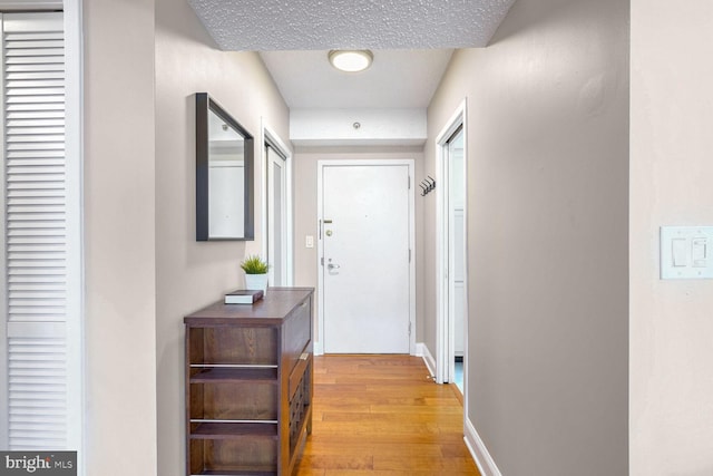 hall with light hardwood / wood-style floors and a textured ceiling