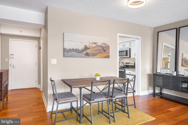 dining room with hardwood / wood-style flooring and a textured ceiling