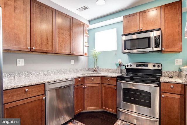 kitchen featuring sink, light stone counters, dark wood-type flooring, and appliances with stainless steel finishes