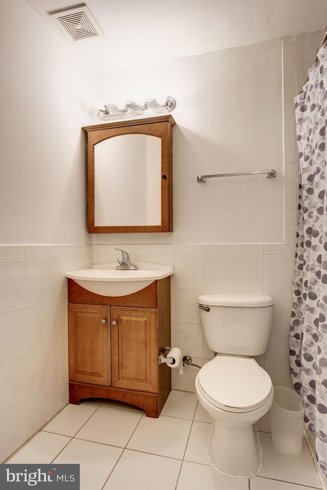 bathroom with tile patterned flooring, vanity, tile walls, and toilet