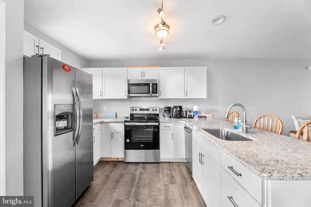 kitchen featuring white cabinets, appliances with stainless steel finishes, kitchen peninsula, and light hardwood / wood-style flooring