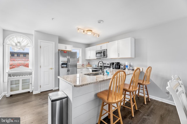 kitchen with a wealth of natural light, white cabinetry, kitchen peninsula, and appliances with stainless steel finishes