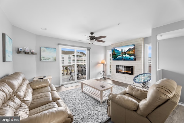 living room with hardwood / wood-style floors, ceiling fan, and a large fireplace