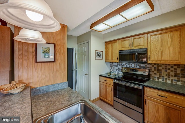 kitchen with decorative backsplash, appliances with stainless steel finishes, and light tile patterned flooring