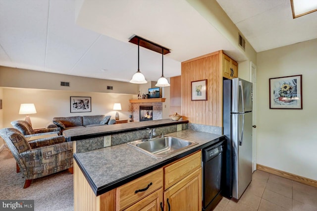 kitchen with sink, a fireplace, black dishwasher, light tile patterned flooring, and stainless steel refrigerator