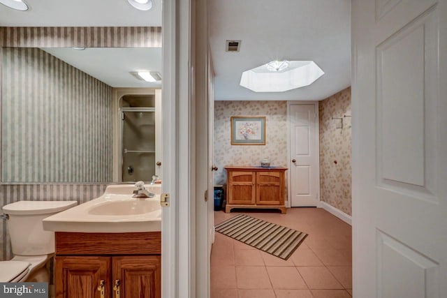 bathroom featuring vanity, a shower, a skylight, tile patterned flooring, and toilet