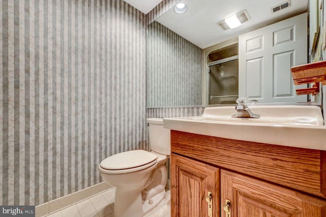 bathroom featuring tile patterned flooring, vanity, a shower with shower door, and toilet