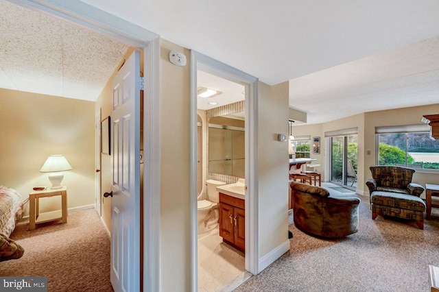 hallway featuring light colored carpet and a textured ceiling