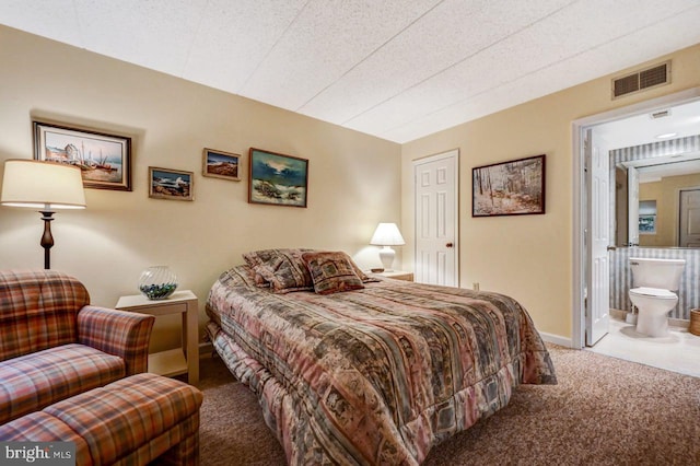 carpeted bedroom featuring a textured ceiling and ensuite bath