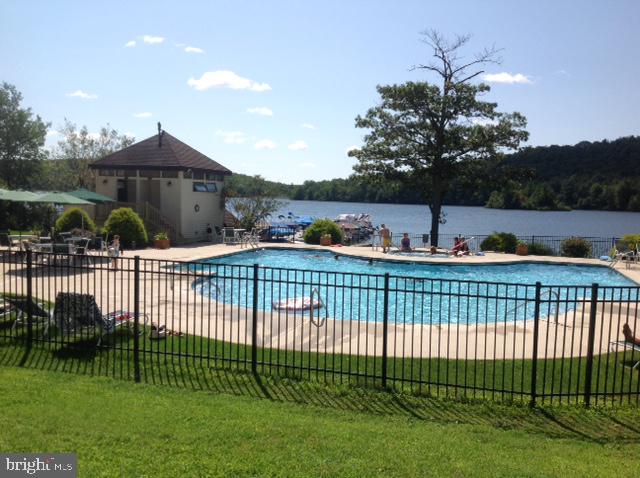 view of swimming pool with a yard, a patio, and a water view