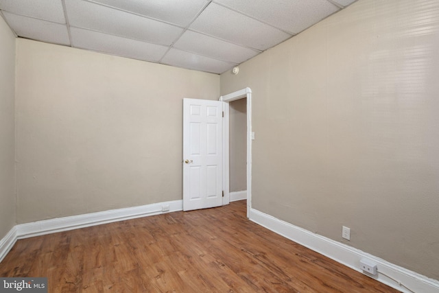 spare room with a paneled ceiling and hardwood / wood-style flooring