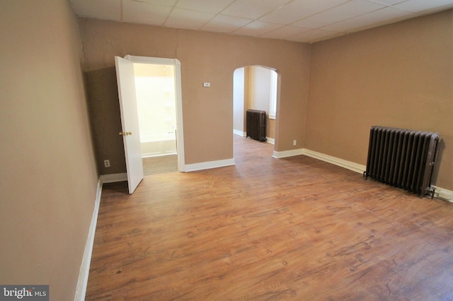 spare room with hardwood / wood-style flooring, a paneled ceiling, and radiator