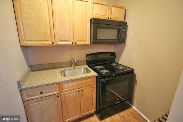 kitchen featuring light stone countertops, sink, black appliances, and light hardwood / wood-style floors