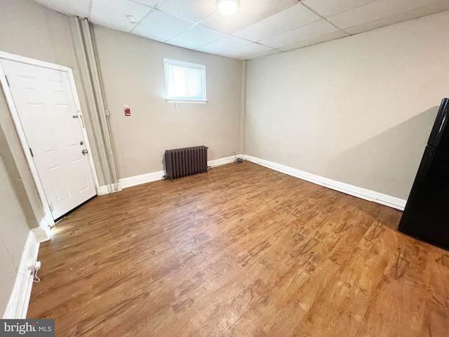 spare room with hardwood / wood-style floors, a paneled ceiling, and radiator