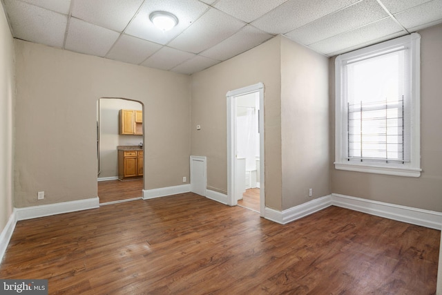 spare room featuring a paneled ceiling and dark hardwood / wood-style flooring