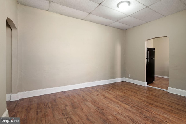 empty room featuring wood-type flooring and a drop ceiling