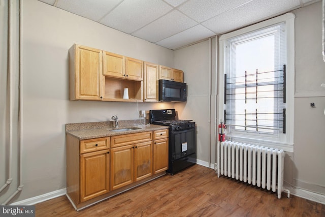 kitchen featuring a drop ceiling, radiator, black appliances, sink, and dark hardwood / wood-style flooring