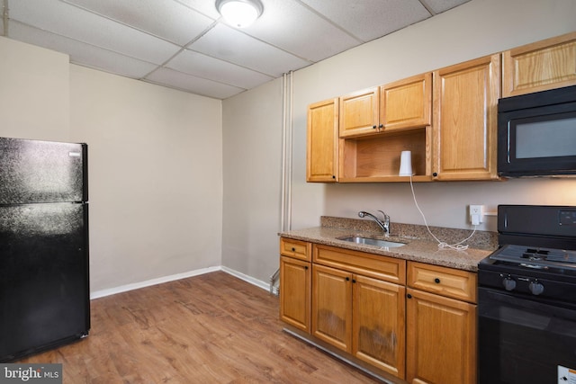 kitchen featuring sink, dark stone countertops, wood-type flooring, a paneled ceiling, and black appliances