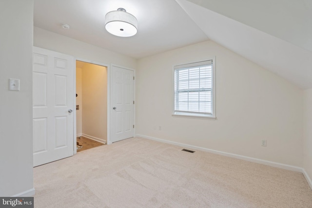 additional living space featuring light colored carpet and lofted ceiling