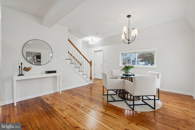 dining space with beamed ceiling, a notable chandelier, and wood-type flooring