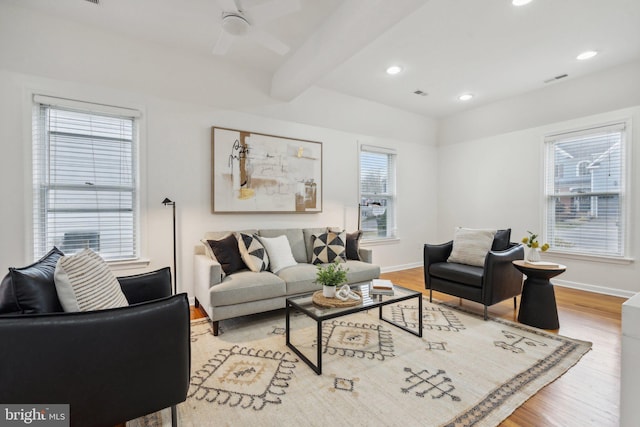 living room with ceiling fan, light hardwood / wood-style floors, and beam ceiling