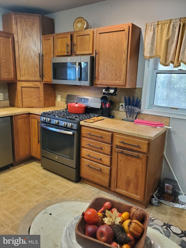 103 Lowden St, Delran, NJ 08075 - kitchen featuring appliances with stainless steel finishes, tasteful backsplash, light countertops, and brown cabinets