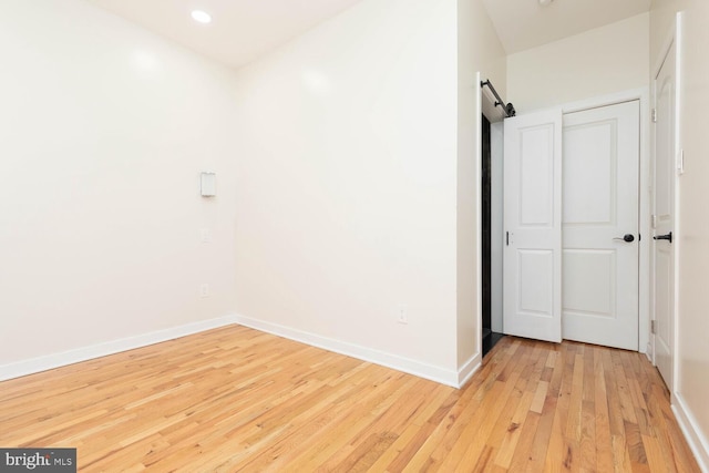 empty room featuring a barn door and light wood-type flooring