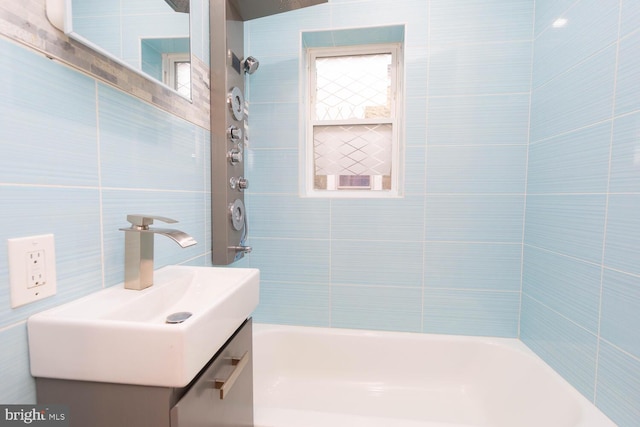 bathroom with tiled shower / bath, vanity, and tile walls