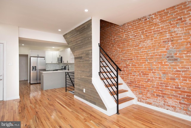 stairway featuring wood-type flooring and brick wall