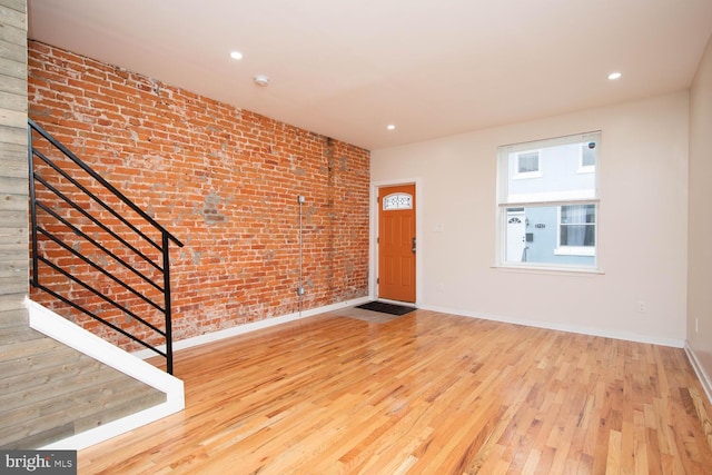 entryway with wood-type flooring and brick wall