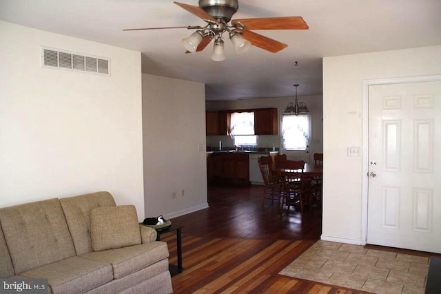 living room featuring dark wood-type flooring and ceiling fan with notable chandelier