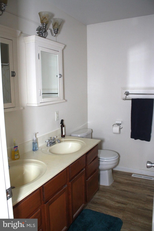 bathroom with toilet, vanity, and hardwood / wood-style flooring