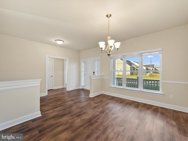 unfurnished dining area with dark hardwood / wood-style floors and an inviting chandelier