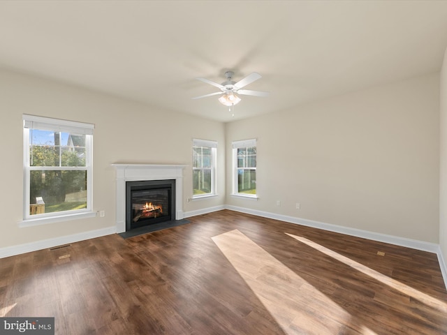 unfurnished living room with ceiling fan, a healthy amount of sunlight, and dark hardwood / wood-style floors