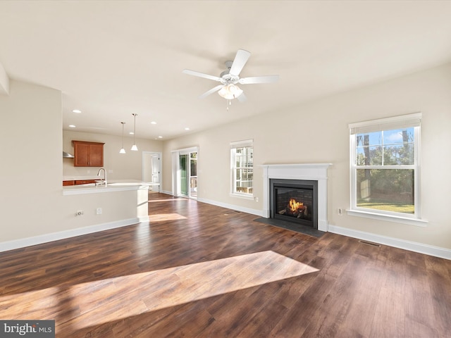 unfurnished living room featuring dark hardwood / wood-style flooring, ceiling fan, and a healthy amount of sunlight