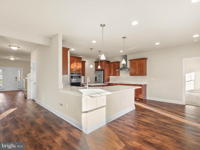 kitchen featuring hanging light fixtures, dark wood-type flooring, wall chimney exhaust hood, and stainless steel appliances