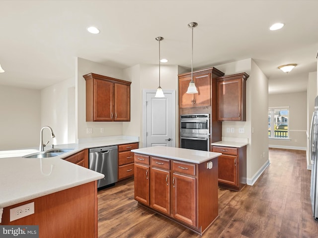 kitchen with dark wood-type flooring, sink, appliances with stainless steel finishes, decorative light fixtures, and kitchen peninsula