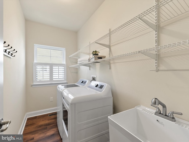 laundry area with washing machine and clothes dryer, dark hardwood / wood-style floors, and sink